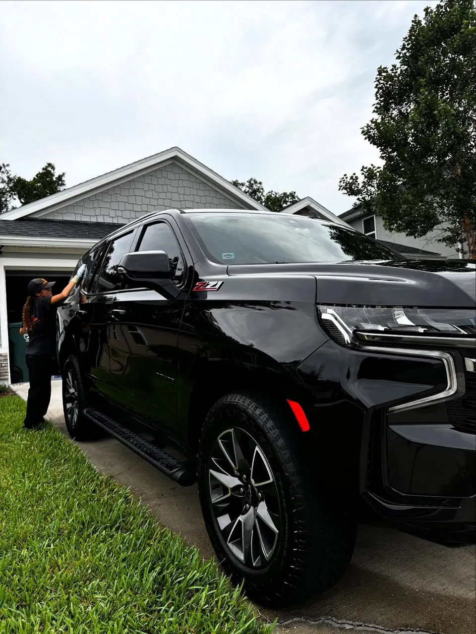 Slick Shine detailer hand-drying a black Chevrolet SUV in a customer’s driveway